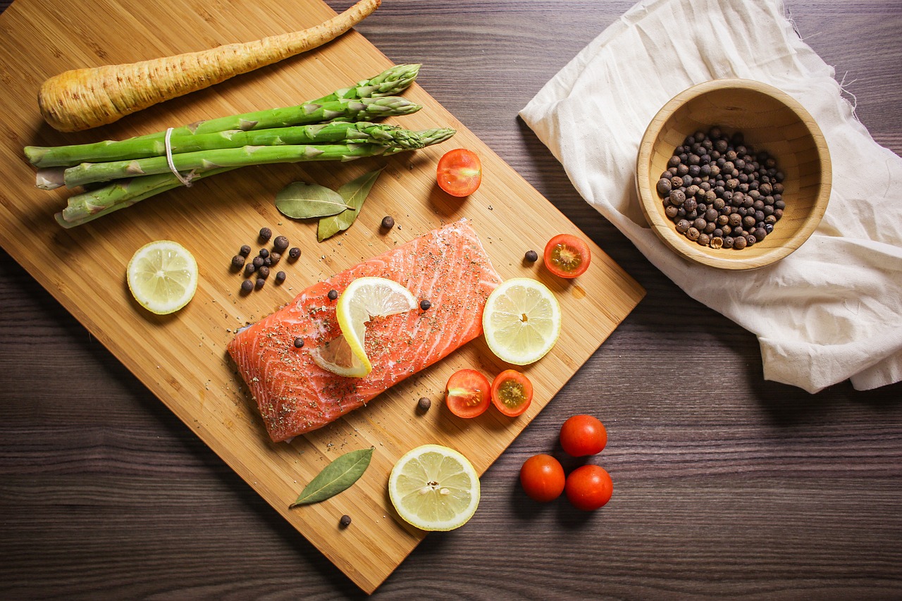 Salmón con verduras e una tabla y algunos otros ingredientes.