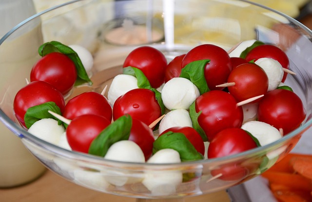 Fuente de cristal redondo con ensalada de tomates cherries y bolitas de queso, para servir en pinchos