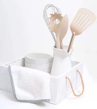 Kit básico de cocina para principiantes con utensilios, cuencos y paño de cocina en una caja blanca, ideal para estudiantes o personas que empiezan a cocinar de forma autónoma.