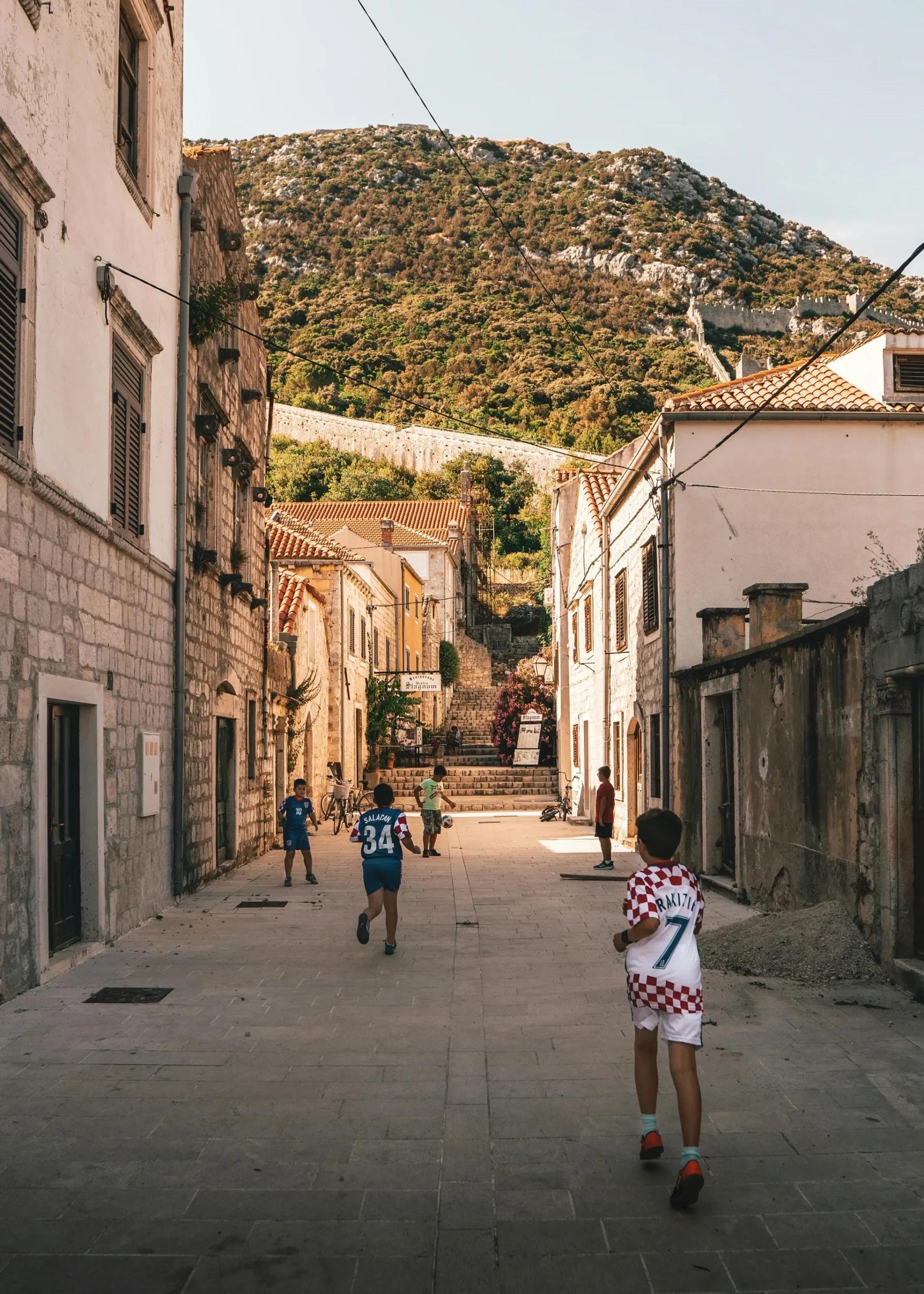 Varios niós están jugando en la calle de su pueblo, a la pelota. 