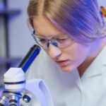 una doctora concentrada mirando a través de un microscopio