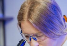 una doctora concentrada mirando a través de un microscopio