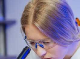 una doctora concentrada mirando a través de un microscopio