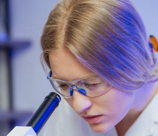 una doctora concentrada mirando a través de un microscopio