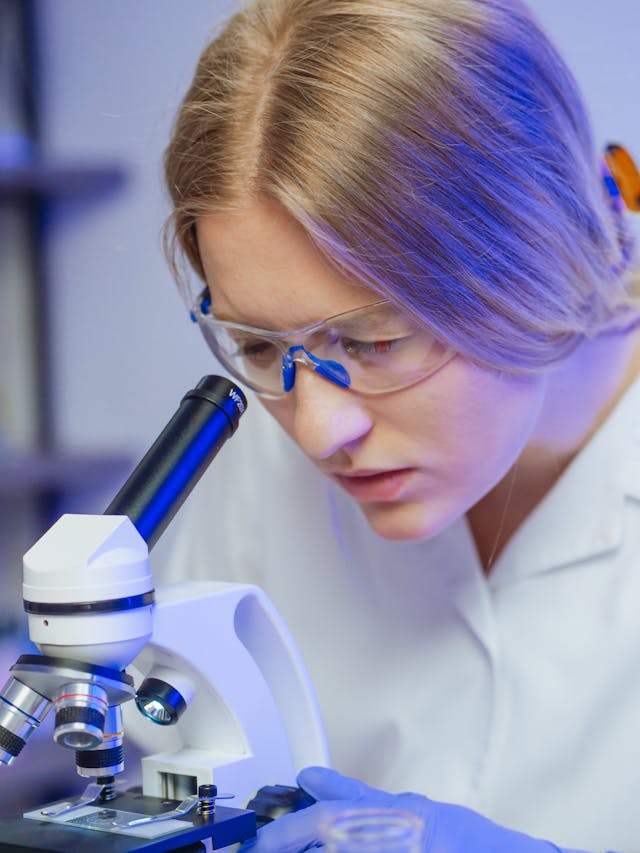 una doctora concentrada mirando a través de un microscopio