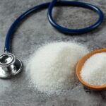 HbA1c y diabetes: ¿siempre refleja bien cómo está nuestra glucosa? Una mesa con una cuchara que contiene azñucar blanca y al lado hay un estetoscopio