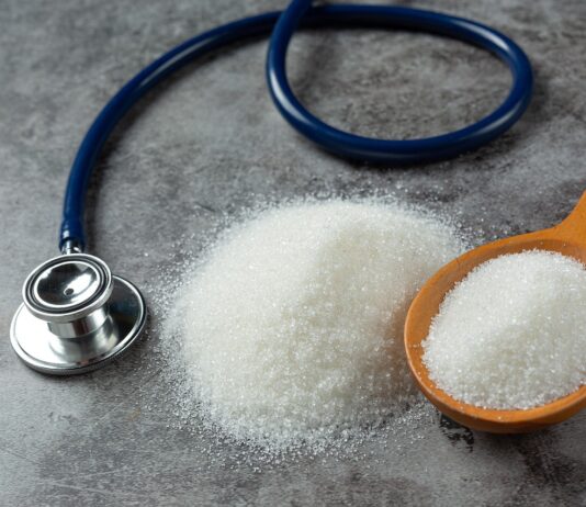 HbA1c y diabetes: ¿siempre refleja bien cómo está nuestra glucosa? Una mesa con una cuchara que contiene azñucar blanca y al lado hay un estetoscopio