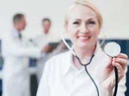 Doctora de medidicina sonriente con un ascultor en la mano.