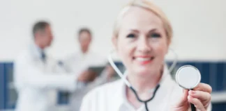 Doctora de medidicina sonriente con un ascultor en la mano.