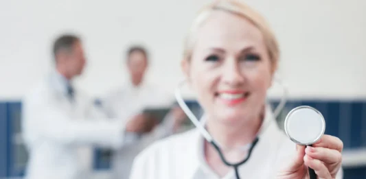Doctora de medidicina sonriente con un ascultor en la mano.