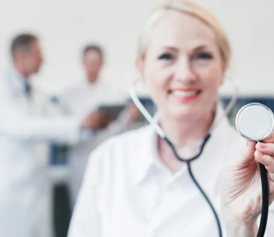 Doctora de medidicina sonriente con un ascultor en la mano.