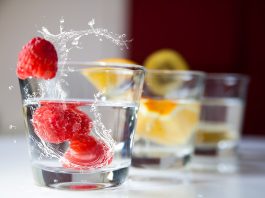 Vasos de agua con frambuesas frescas y rodajas de cítricos, alternativa saludable para hidratarse en personas con diabetes