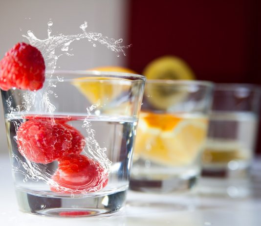 Vasos de agua con frambuesas frescas y rodajas de cítricos, alternativa saludable para hidratarse en personas con diabetes