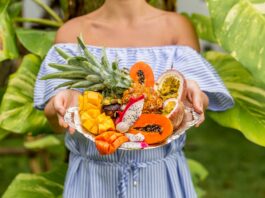 Bandeja sostenida por una mujer joven con frutas exóticas y tropicales, so