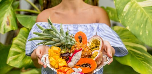 Bandeja sostenida por una mujer joven con frutas exóticas y tropicales, so