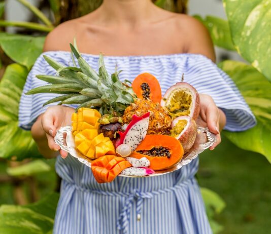 Bandeja sostenida por una mujer joven con frutas exóticas y tropicales, so