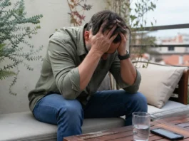 Persona con estrés emocional sentada en la terraza de casa, con la cabeza entre las manos, representando el burnout en diabetes y el agotamiento mental cotidiano