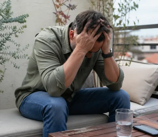 Burnout en diabetes: cuando el cansancio va más allá del trabajo Persona con estrés emocional sentada en la terraza de casa, con la cabeza entre las manos, representando el burnout en diabetes y el agotamiento mental cotidiano
