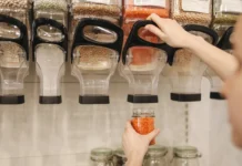 Cómo afectan los cereales y las legumbres a tu salud y a la diabetes Dispensadores de legumbres, la mano de una chica se ve sirviendose de uno de ellos.