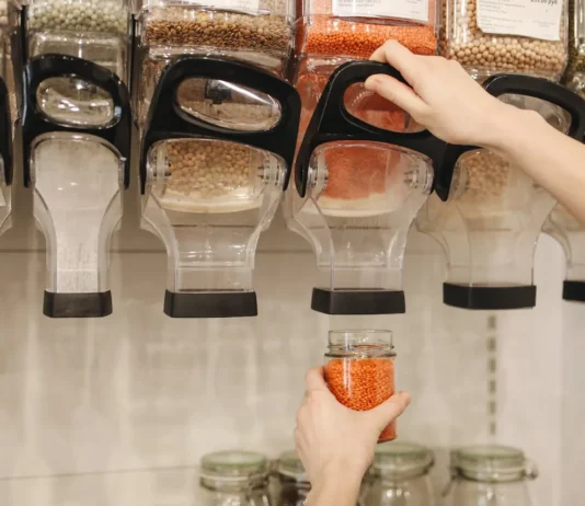 Dispensadores de legumbres, la mano de una chica se ve sirviendose de uno de ellos.