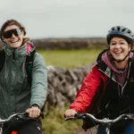 Dos ciclistas en bicicletas de montaña saludan alegremente a la cámara
