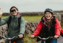 Dos ciclistas en bicicletas de montaña saludan alegremente a la cámara