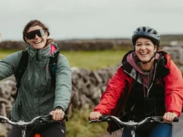Dos ciclistas en bicicletas de montaña saludan alegremente a la cámara