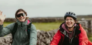 Dos ciclistas en bicicletas de montaña saludan alegremente a la cámara
