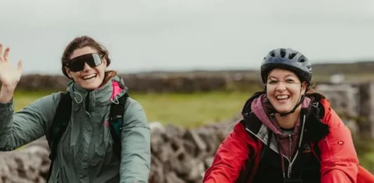 Dos ciclistas en bicicletas de montaña saludan alegremente a la cámara