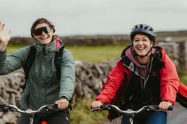 Dos ciclistas en bicicletas de montaña saludan alegremente a la cámara
