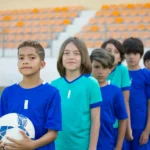 equipo de futbol infantil listos para salir al campo, en fila y miando a la cámara