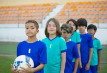 equipo de futbol infantil listos para salir al campo, en fila y miando a la cámara