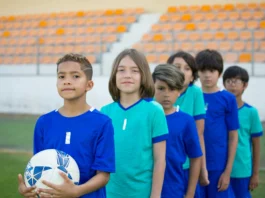 equipo de futbol infantil listos para salir al campo, en fila y miando a la cámara