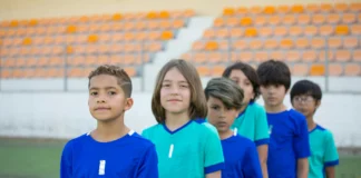 equipo de futbol infantil listos para salir al campo, en fila y miando a la cámara