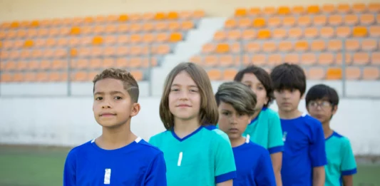 equipo de futbol infantil listos para salir al campo, en fila y miando a la cámara