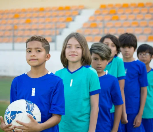 equipo de futbol infantil listos para salir al campo, en fila y miando a la cámara
