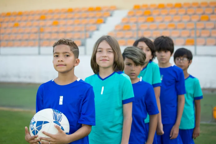 equipo de futbol infantil listos para salir al campo, en fila y miando a la cámara