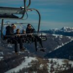 Diabetes y viajes de invierno: cómo prepararte Una familia joven, con sus dos niños pequeños van en una telesilla, subiendo a las pista de esquí
