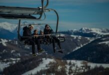 Diabetes y viajes de invierno: cómo prepararte Una familia joven, con sus dos niños pequeños van en una telesilla, subiendo a las pista de esquí