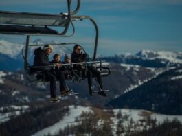 Diabetes y viajes de invierno: cómo prepararte Una familia joven, con sus dos niños pequeños van en una telesilla, subiendo a las pista de esquí