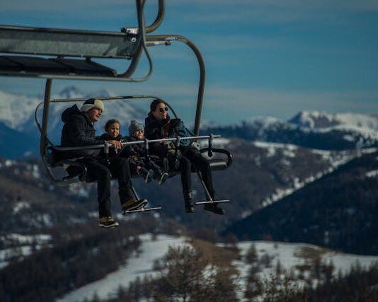 Diabetes y viajes de invierno: cómo prepararte Una familia joven, con sus dos niños pequeños van en una telesilla, subiendo a las pista de esquí
