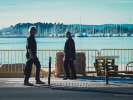 En un paseo marítimo se ven a dos personas, hombres paseando o caminando