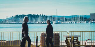 En un paseo marítimo se ven a dos personas, hombres paseando o caminando