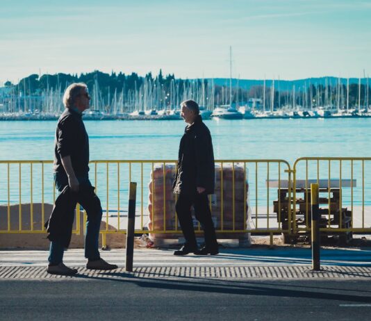 En un paseo marítimo se ven a dos personas, hombres paseando o caminando