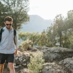 Un hombre joven con gafas caminando en el monte.