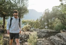 Un hombre joven con gafas caminando en el monte.