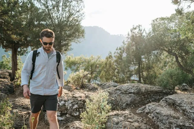 hombre-joven-caminando-naturaleza Un hombre joven con gafas caminando en el monte.