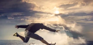 un hombre saltando, sobre un pavimento y un cielo nublado, y un reloj antiguo marcando el tiempo