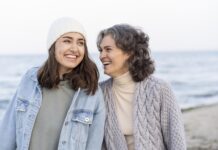 madre e hija sonrientes en un paseo por la playa
