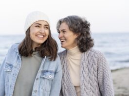 madre e hija sonrientes en un paseo por la playa